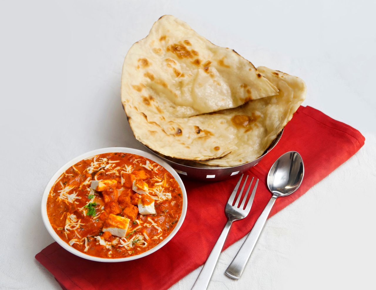 A vibrant and flavorful Indian paneer curry served with fresh naan bread, perfect for dinner.